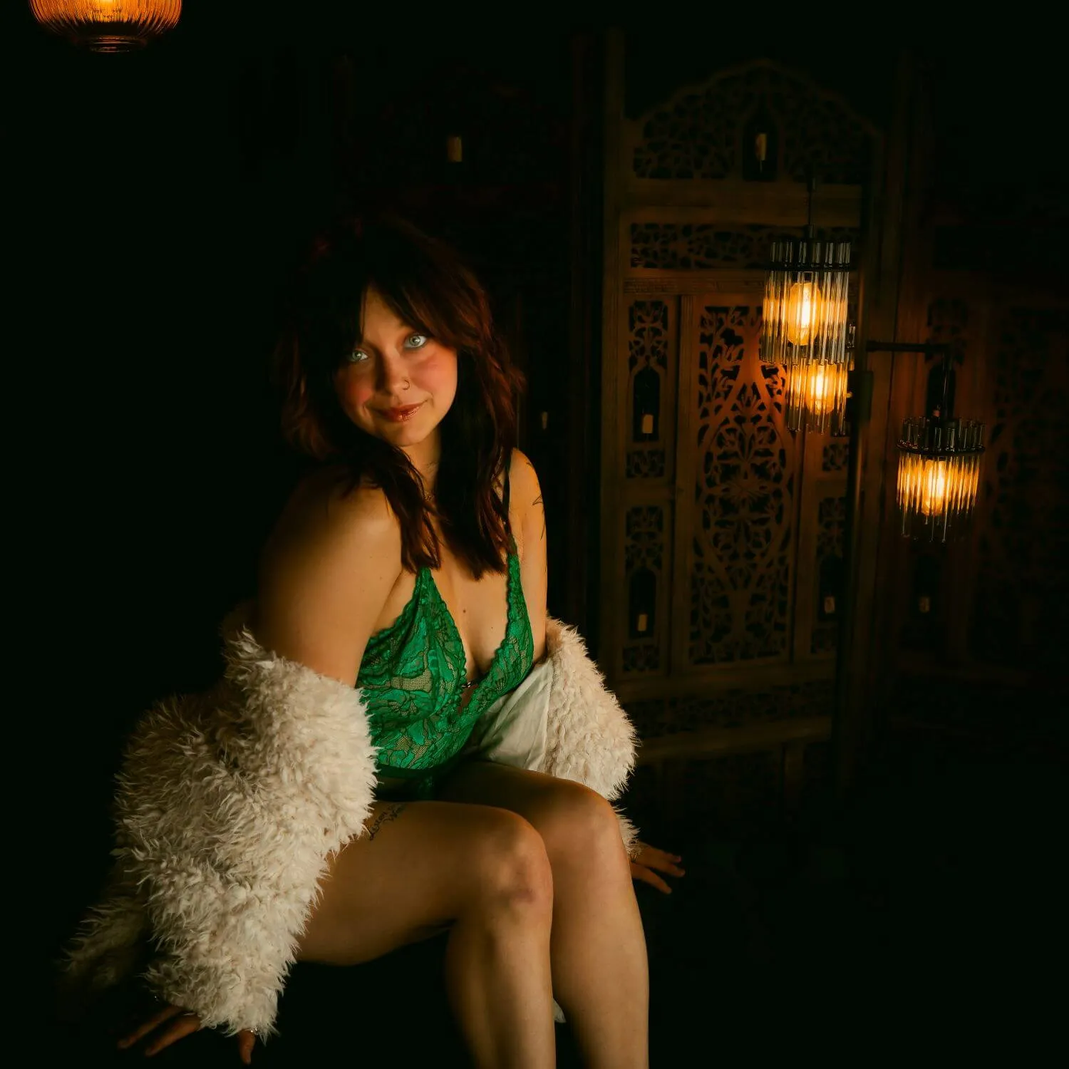Smiling woman in green lingerie, white fur draped around her.