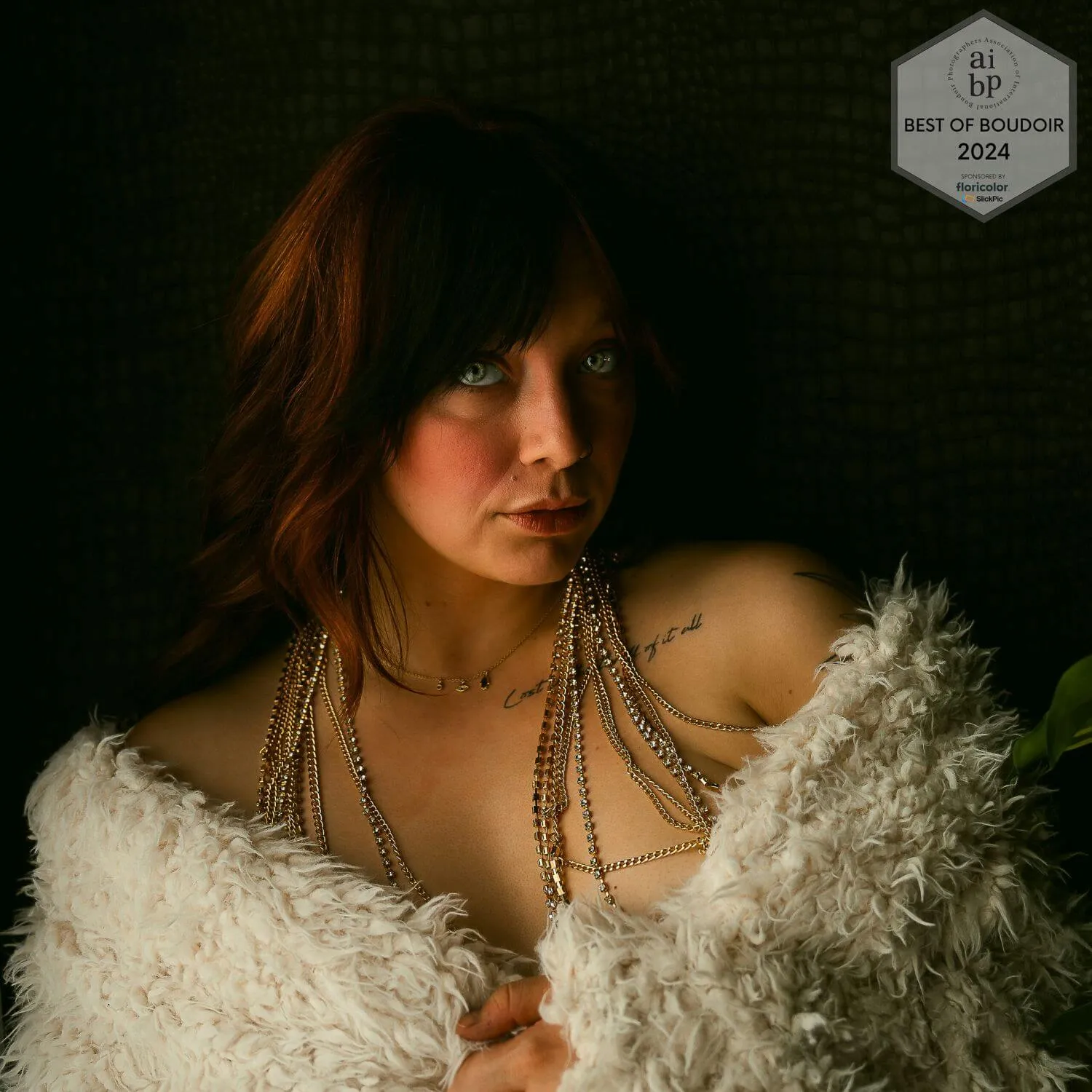 Brunette with striking green eyes wrapped in white fur. Winning image of the AIPB Best of Boudoir 2024 award.