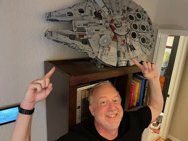 Allan Pickering pointing up at his LEGO Millennium Falcon on display.
