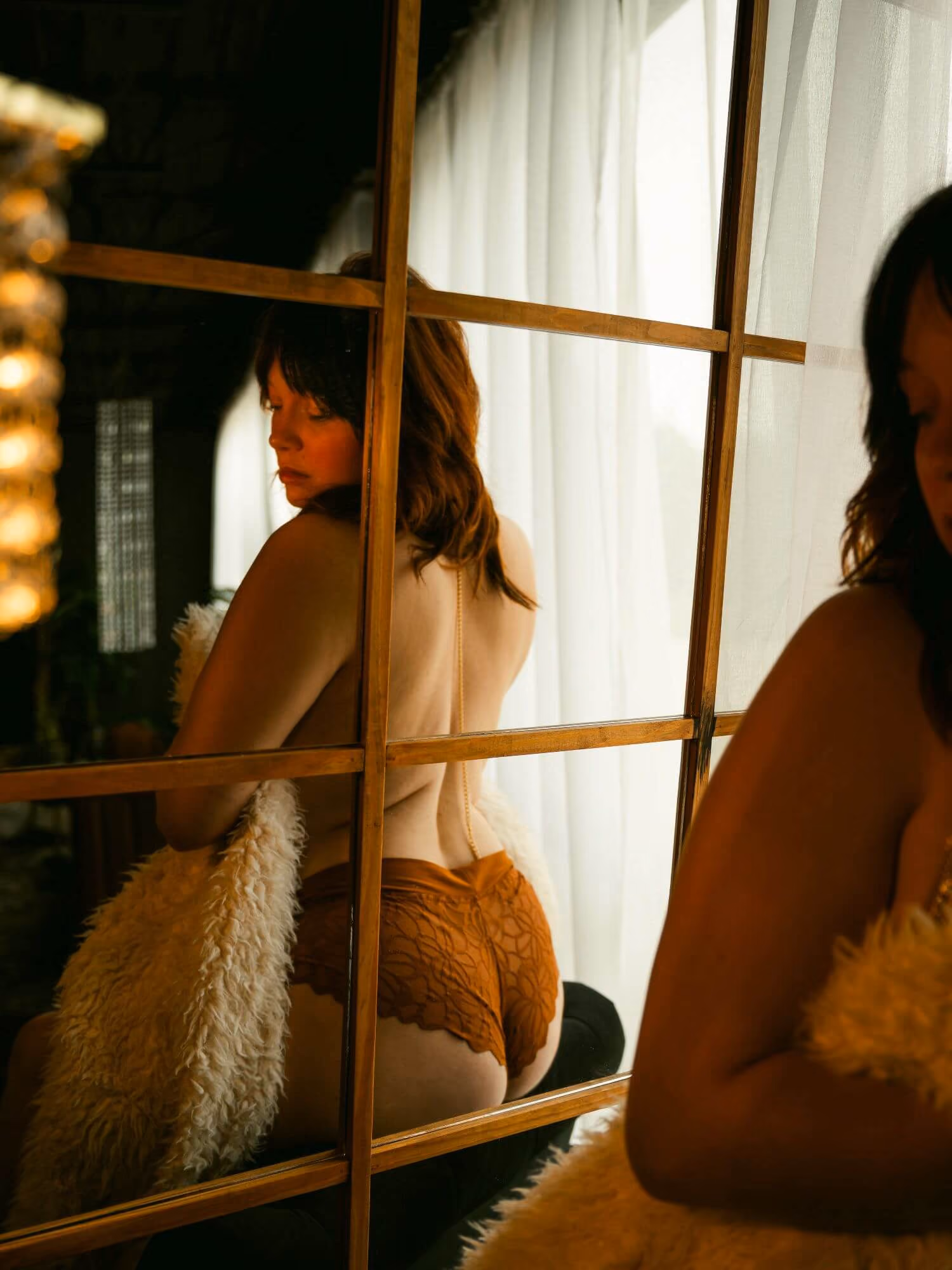 Mirror reflection of a woman wrapped in a fur blanket, looking over her shoulder.