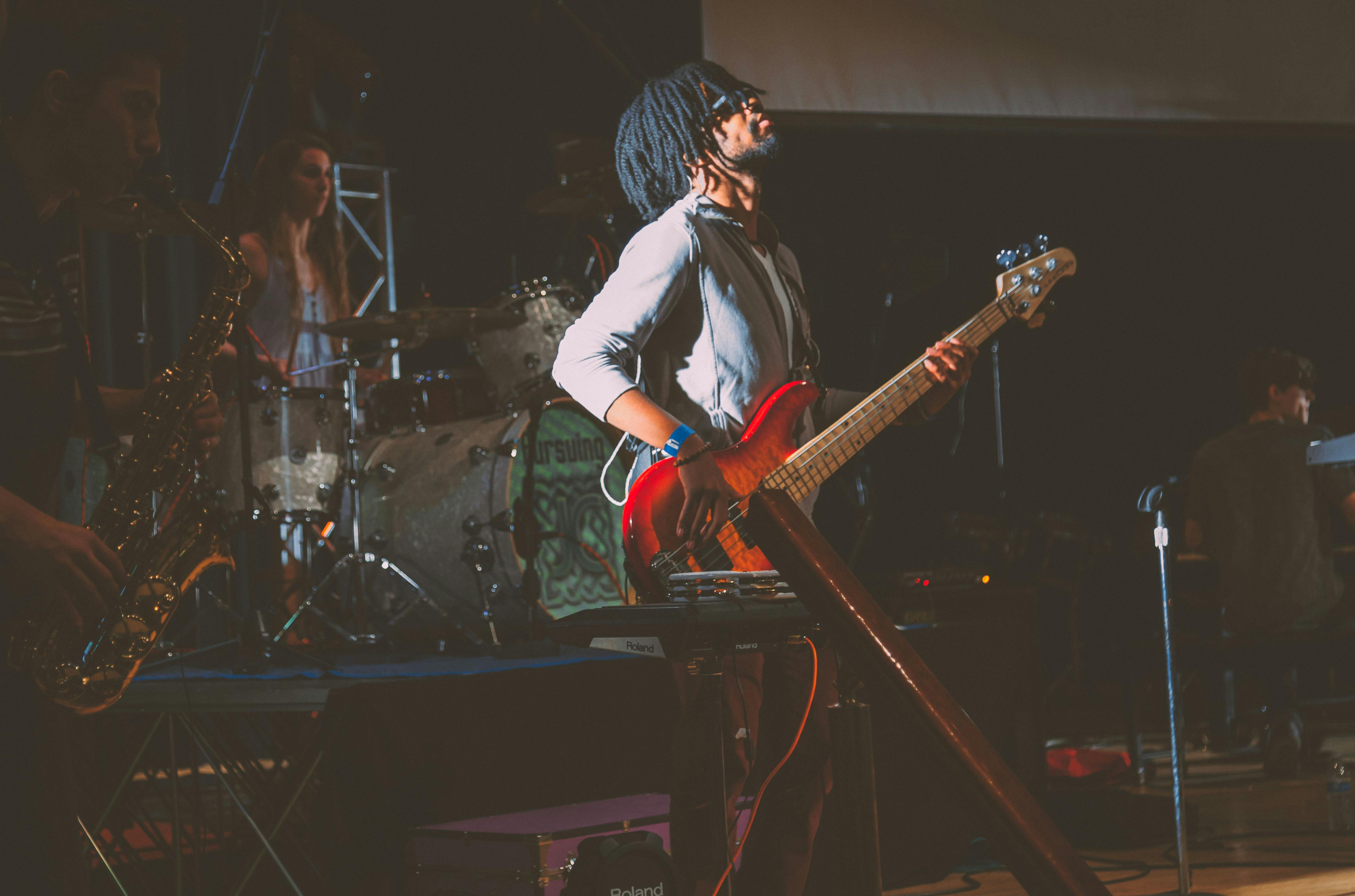 A man playing the electric guitar on stage with his band