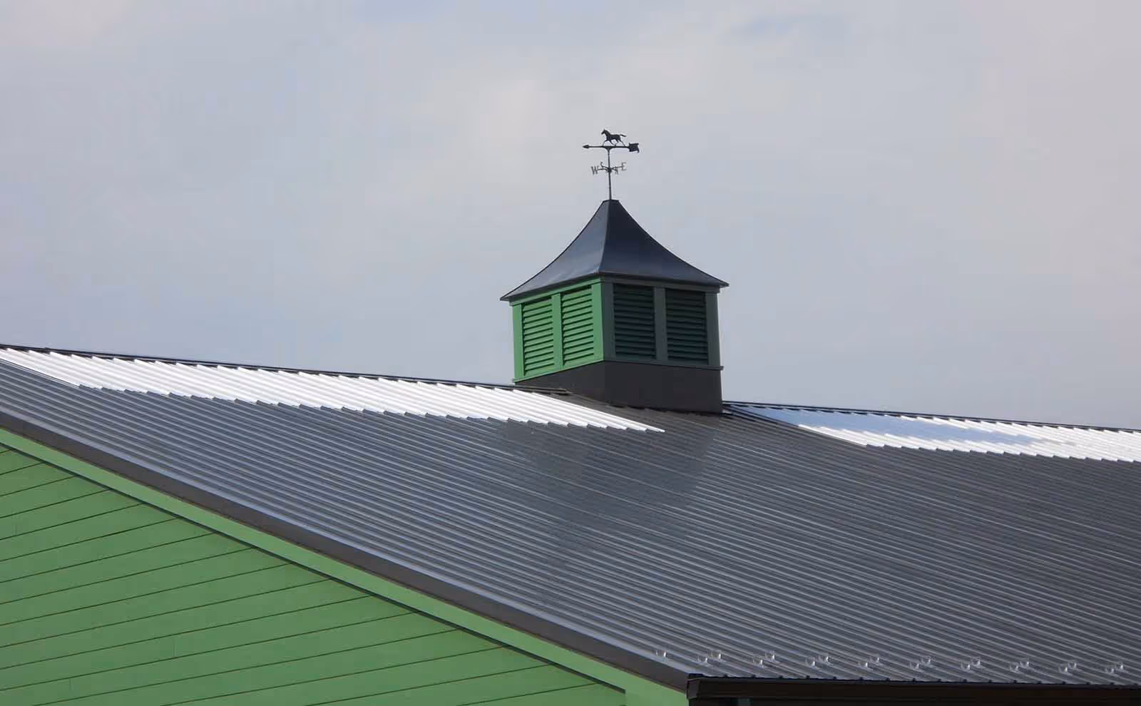 Larger view of a Sundance Series cupola on a metal-roofed building in Franklin, Ohio with louvered green sides and black roof.