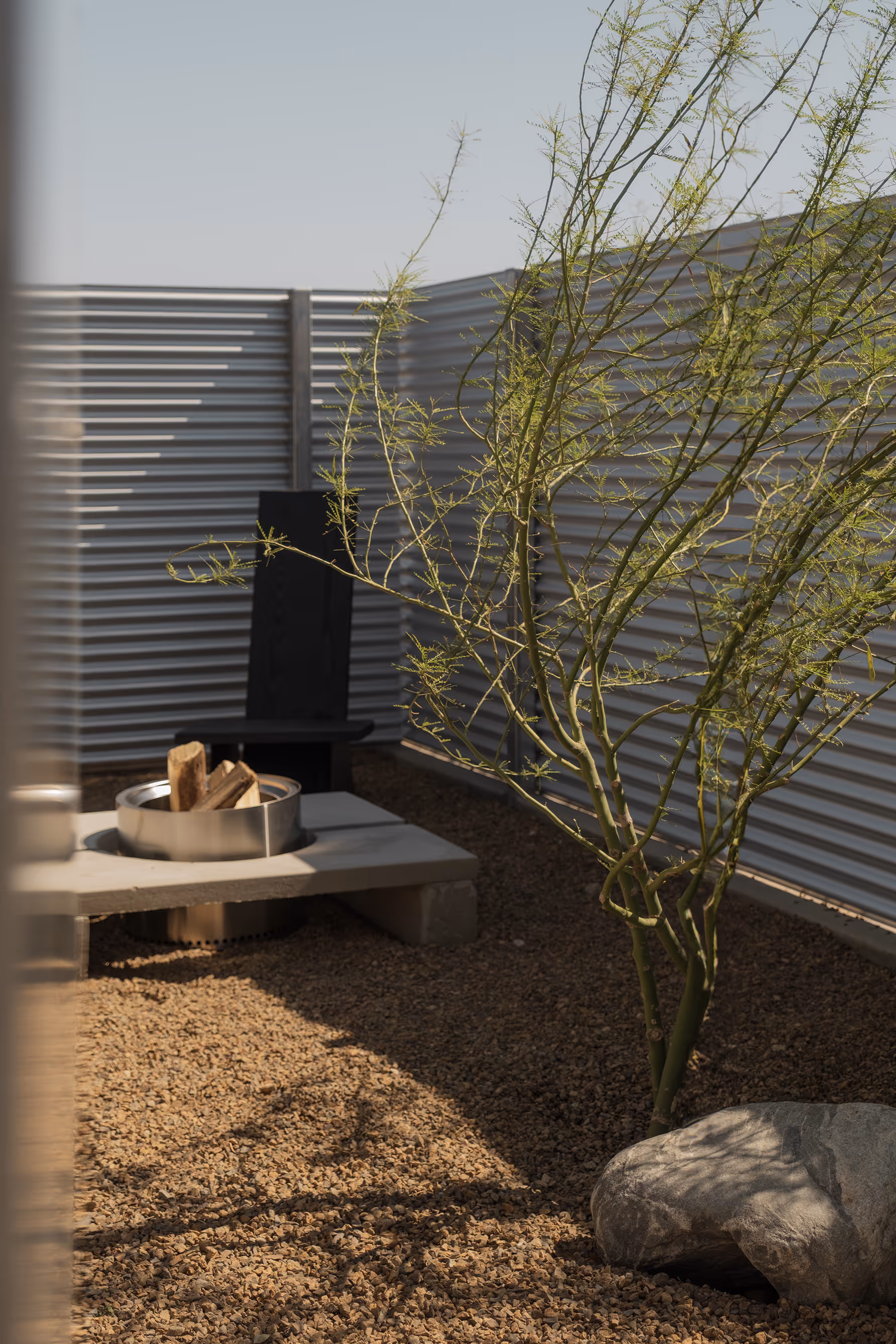 Relaxing fire pit area with chair and tree at Reset Hotel, Twentynine Palms, CA