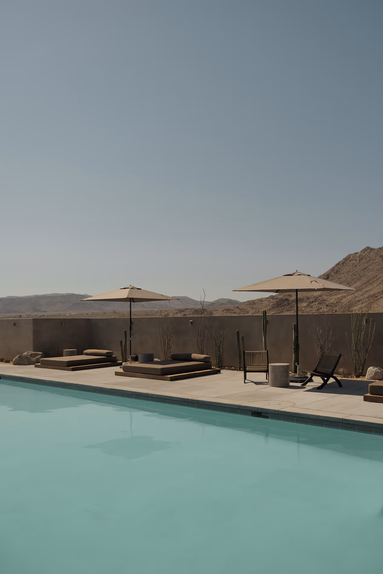 Serene turquoise pool with lounge chairs and desert mountains at Reset Hotel, Twentynine Palms