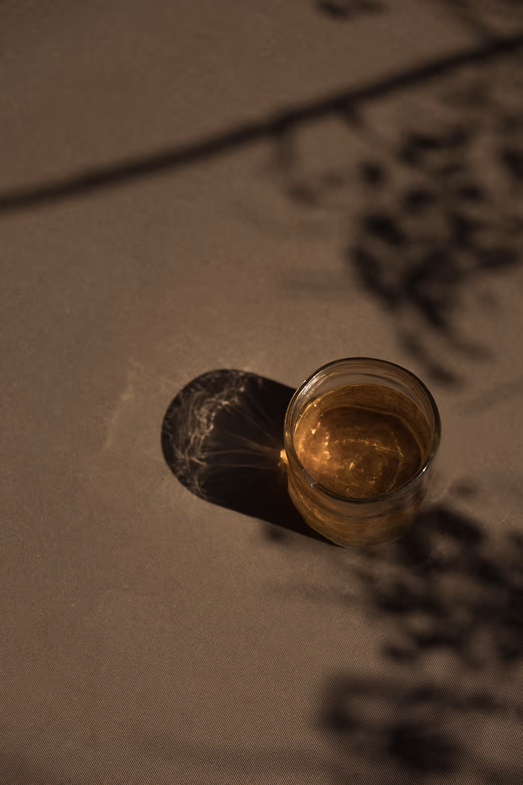 Glass of amber drink casting tree shadows on a table at Reset Hotel, Twentynine Palms.