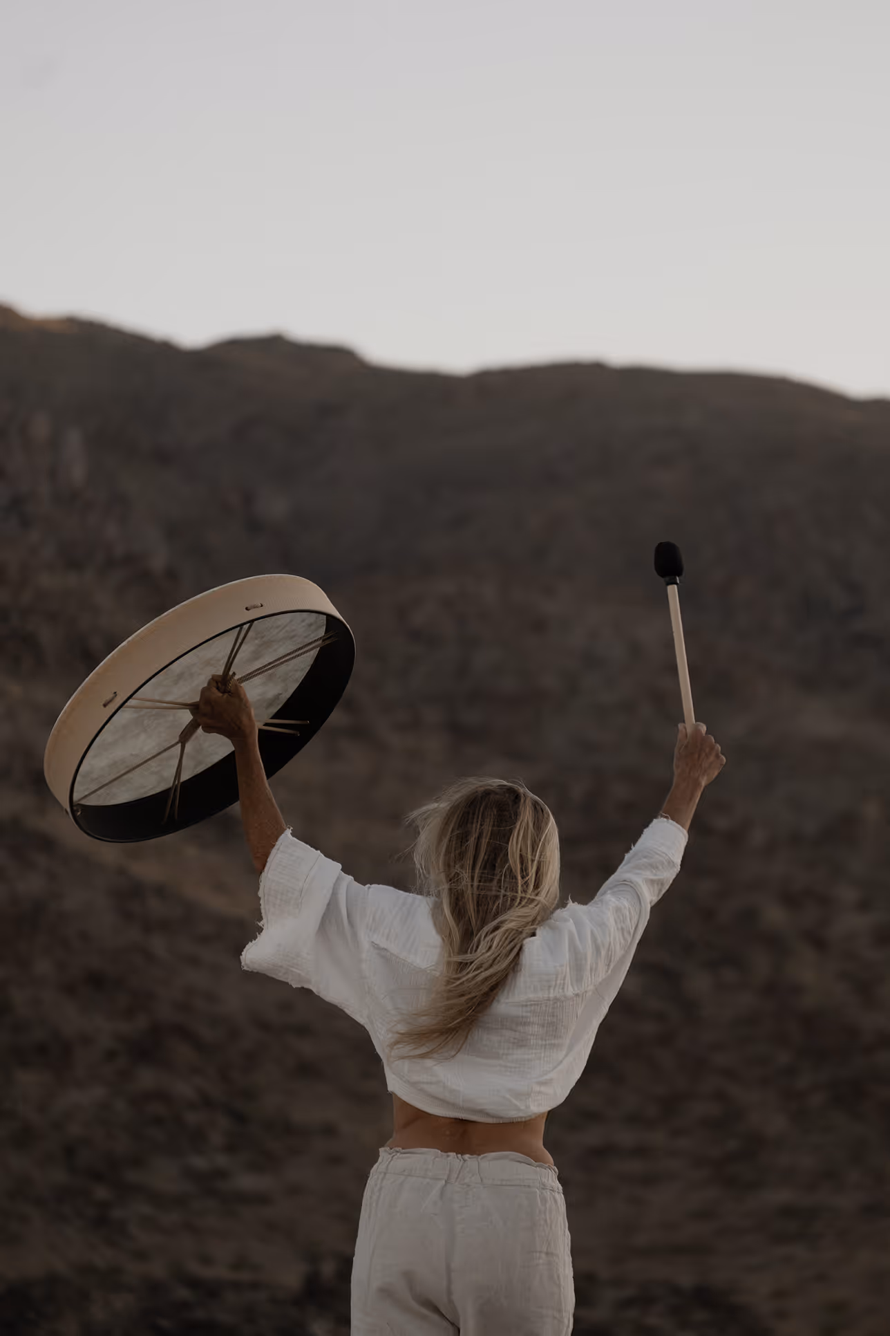 Woman raising a drum outdoors at Reset Hotel with Twentynine Palms mountain views