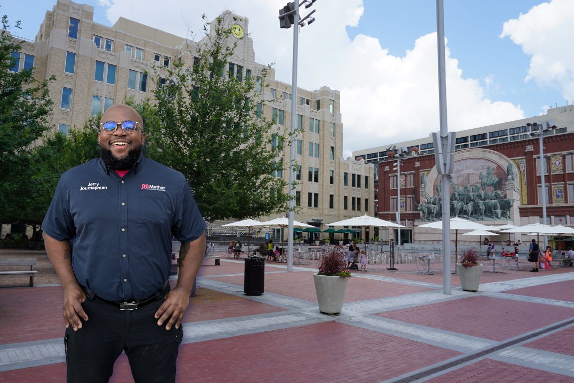 Photo of a uniformed plumber in Fort Worth, TX from Mother Modern Plumbing standing and smiling