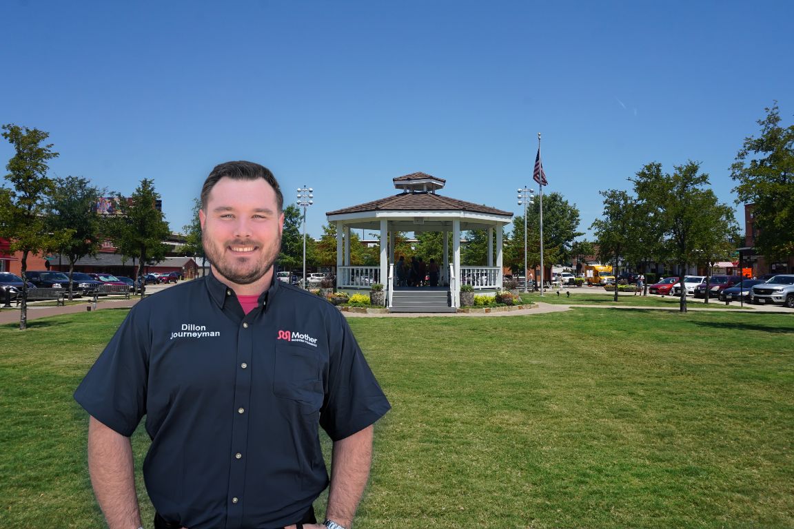 Photo of a uniformed plumber in Carrollton, TX from Mother Modern Plumbing standing and smiling