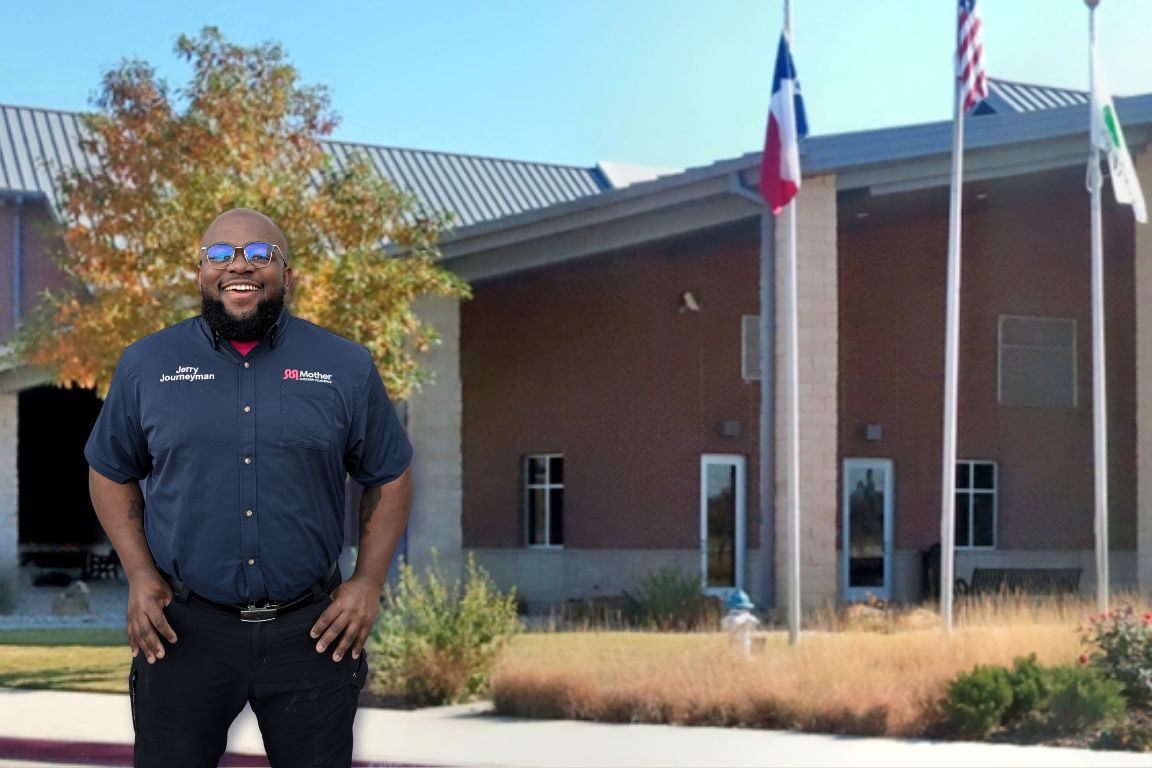 Photo of a uniformed plumber in Flower Mound, TX from Mother Modern Plumbing standing and smiling