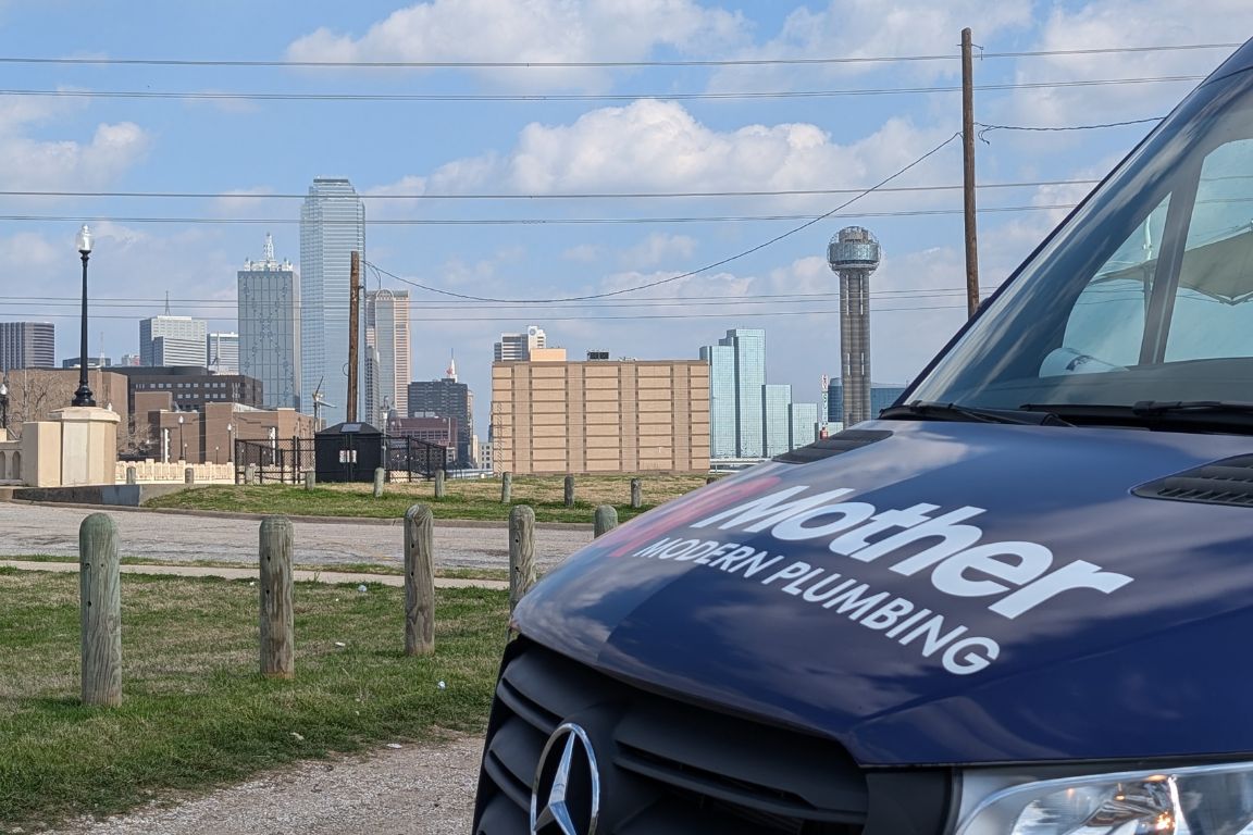 Photo of a uniformed plumber in Dallas, TX from Mother Modern Plumbing standing and smiling