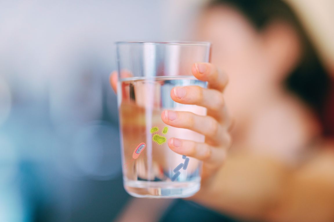 woman holding glass of water from fridge water filter with bacteria and viruses