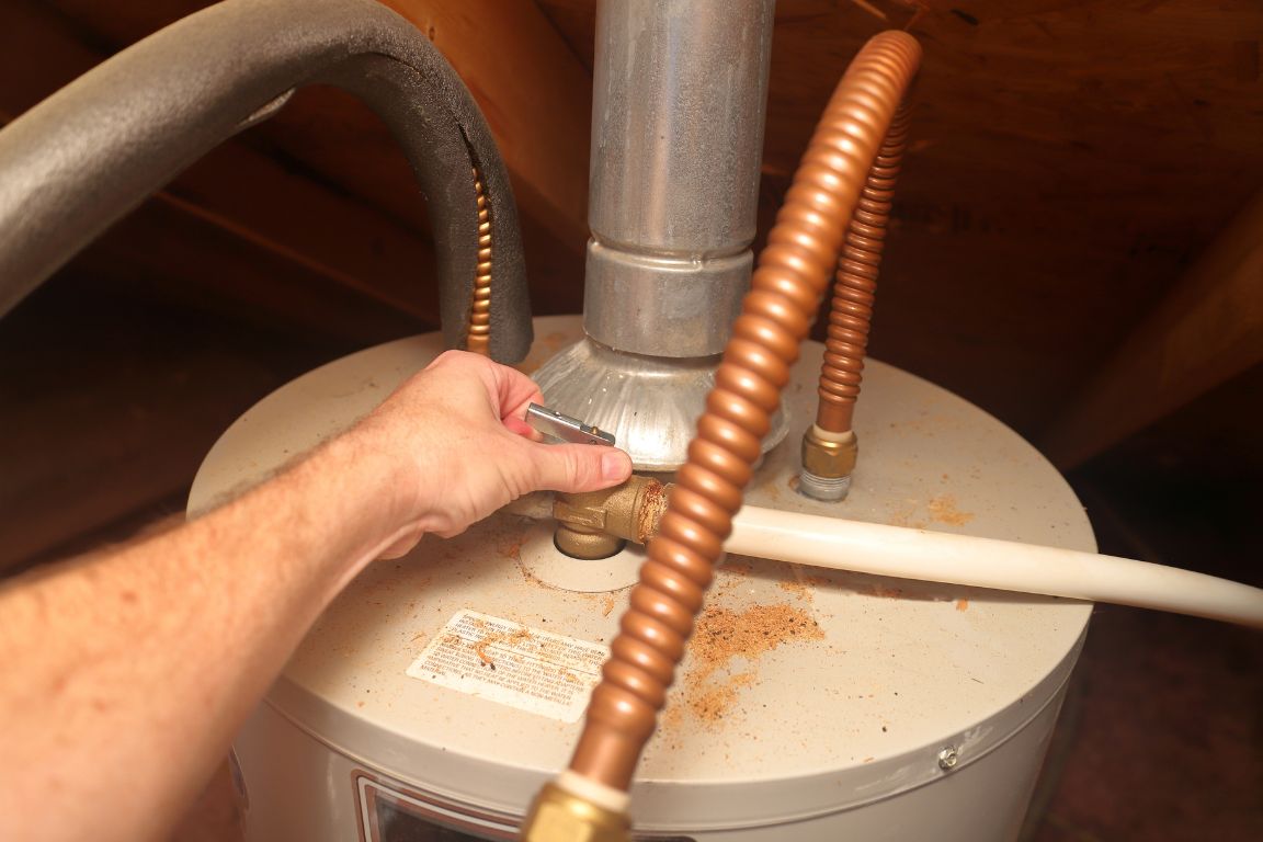 plumber checks leaky t&p valve on top of a water heater tank