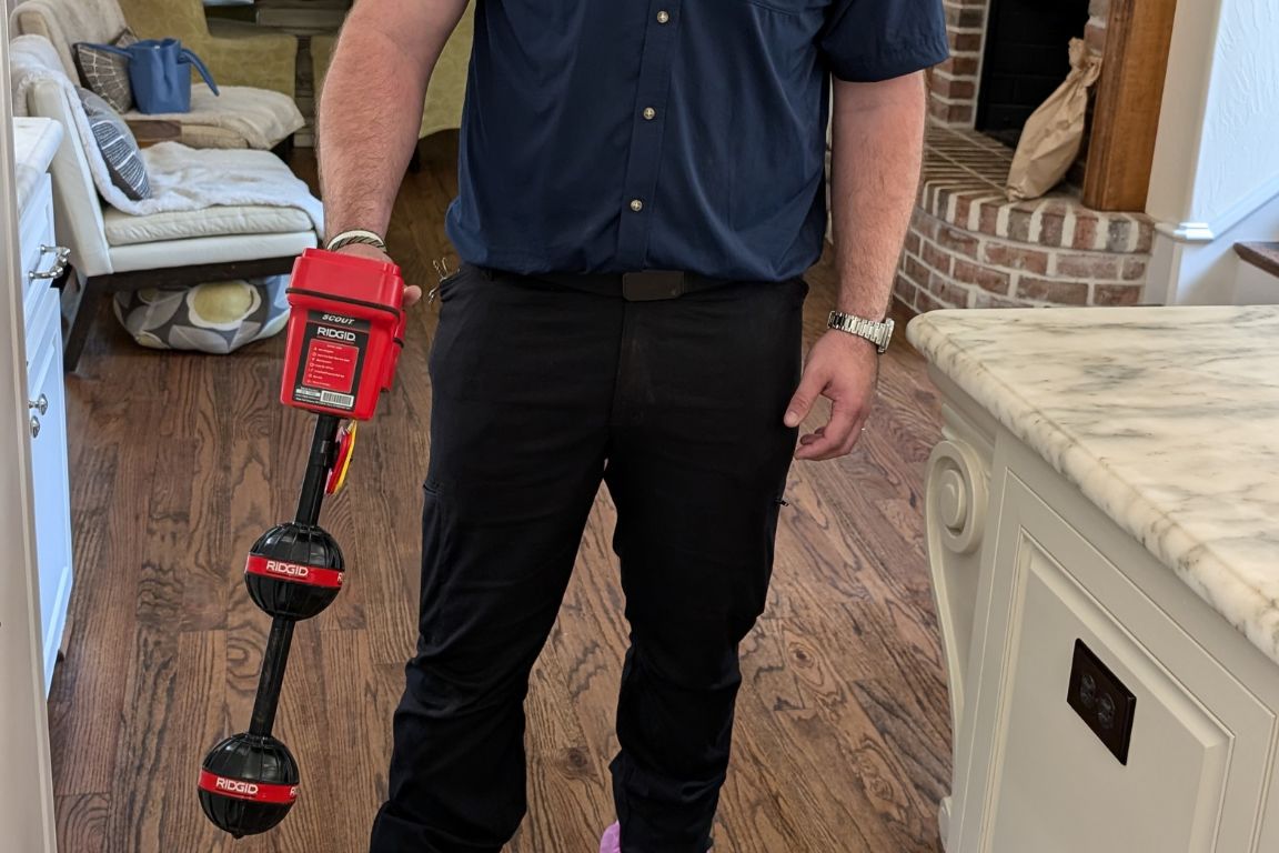 close up of acoustic leak detection tool in hands of uniformed master plumber from mother modern plumbing in highland park, tx living space