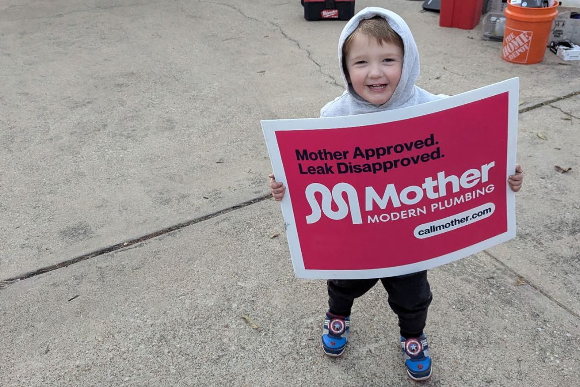 child in gray sweatshirt holds mother modern plumbing leak detection poster and smiles in sachse, tx driveway