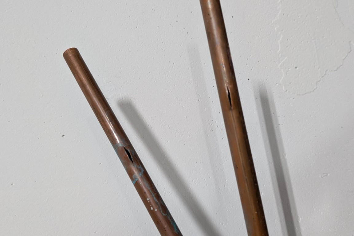 pair of copper water lines removed from wall of hurst, tx kitchen, showing signs of degradation and leaks