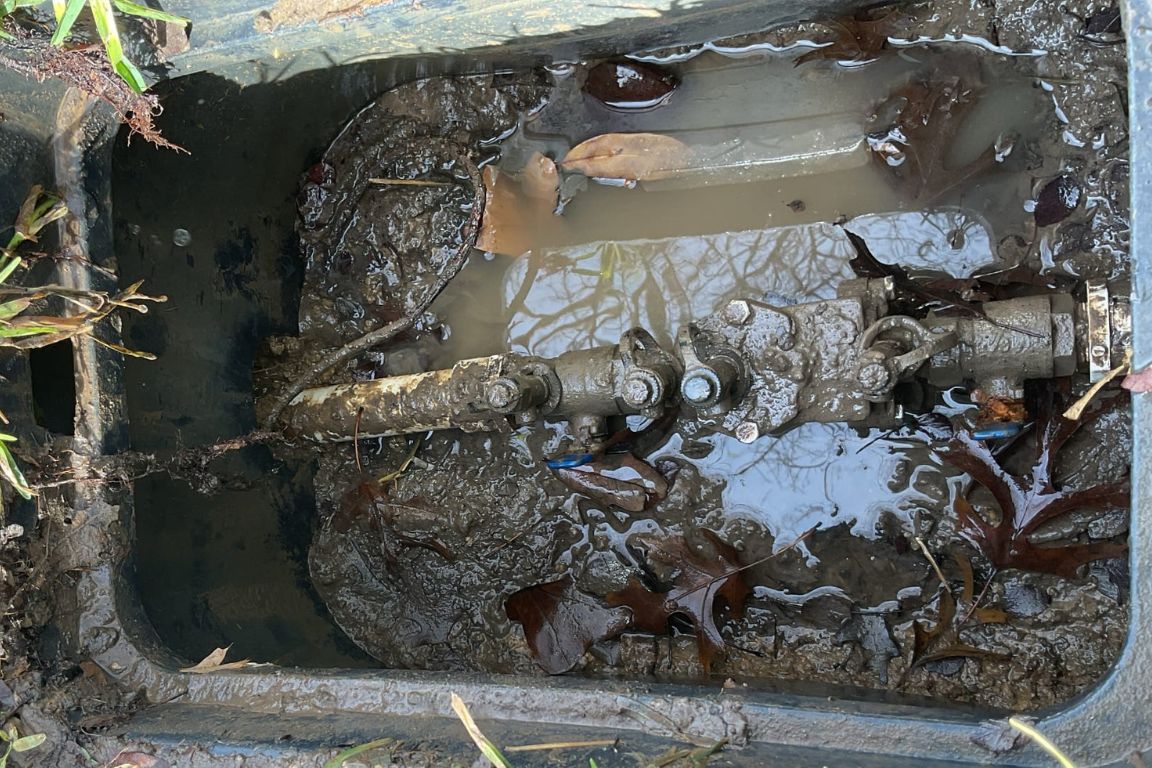 exposed main water supply line in wylie, tx backyard shows leak at pipe connection causing pooling underground