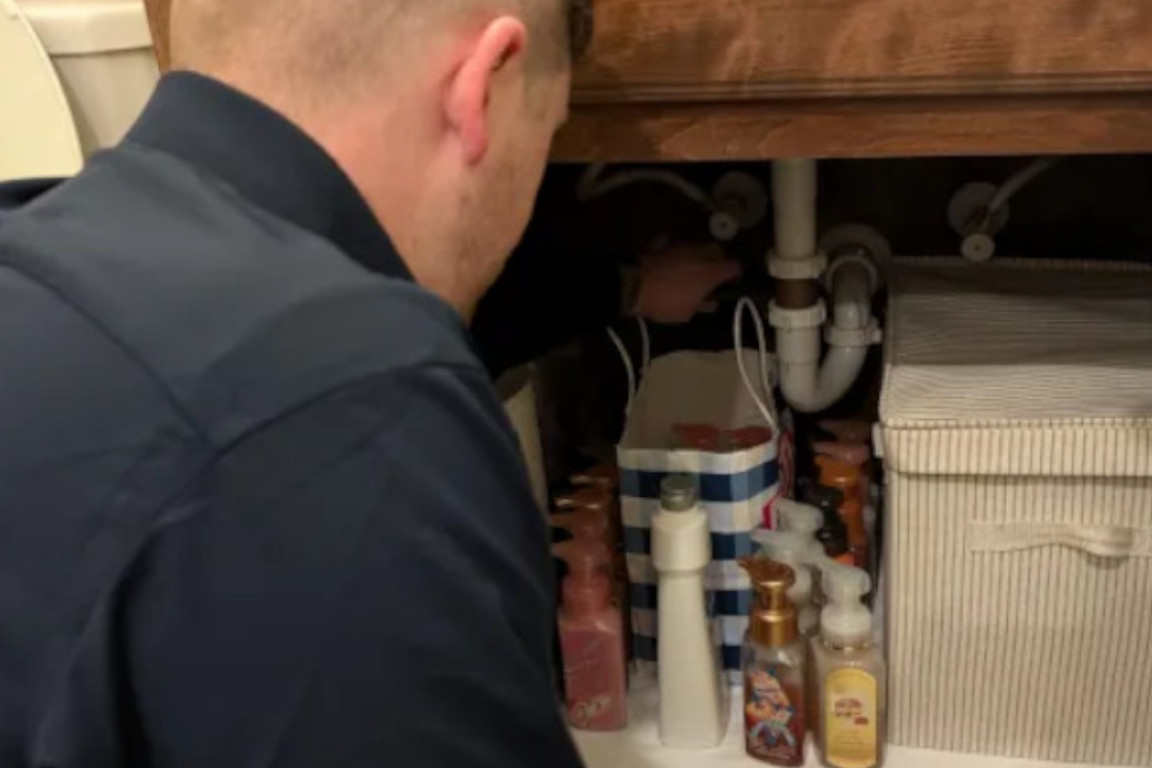 uniformed plumber performs plano tx residential drain cleaning service in master bathroom of home