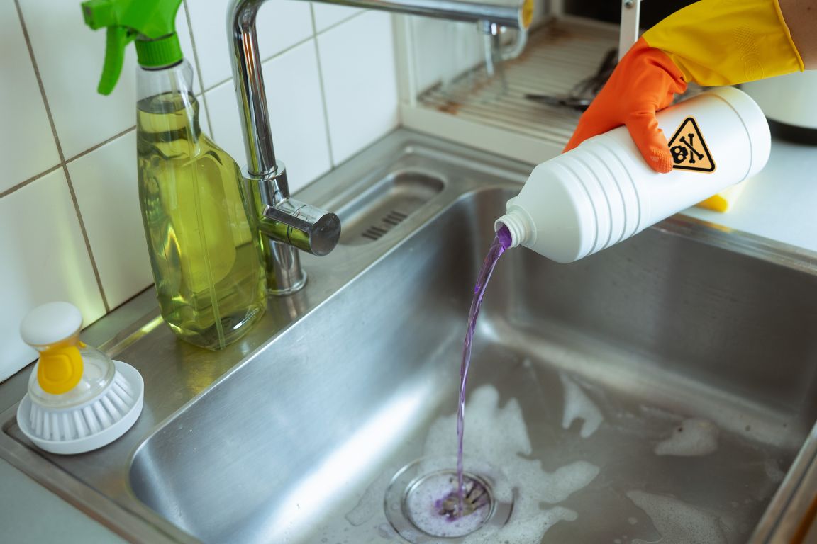 homeowner pours acidic drain cleaner sulfuric acid down kitchen sink drain, inadvisable health and plumbing risk