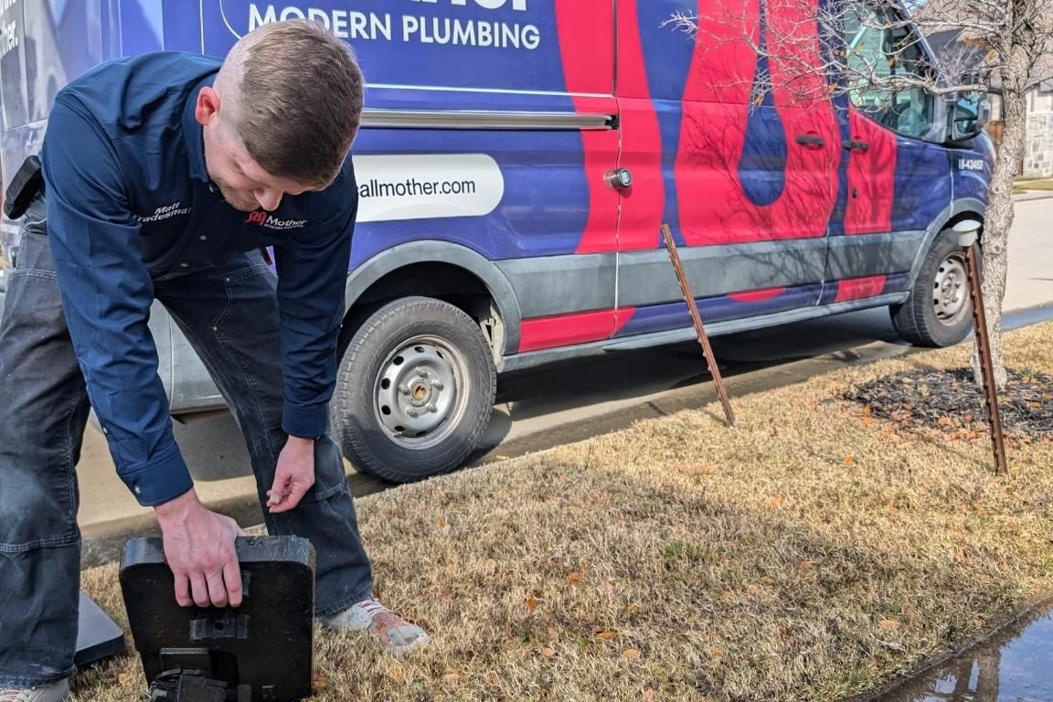 licensed plumber opens meter box on curb to shut off water to house during burst pipe repair, mother modern plumbing