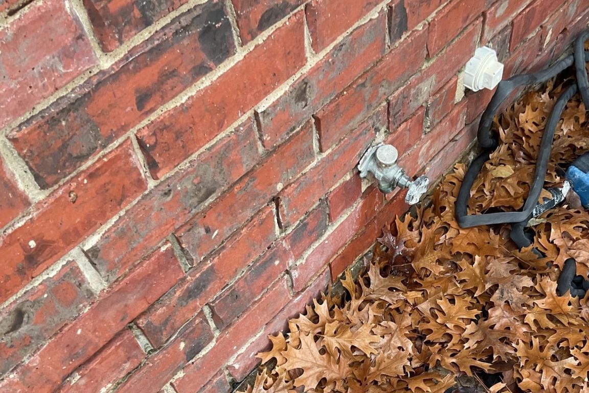frozen outdoor faucet along brick exterior wall of dallas ranch home