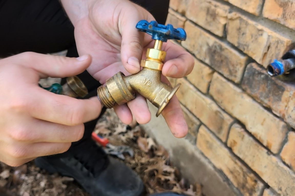 licensed plumber inspects outdoor faucet with ice plug and brass damage prior to hose bib repair