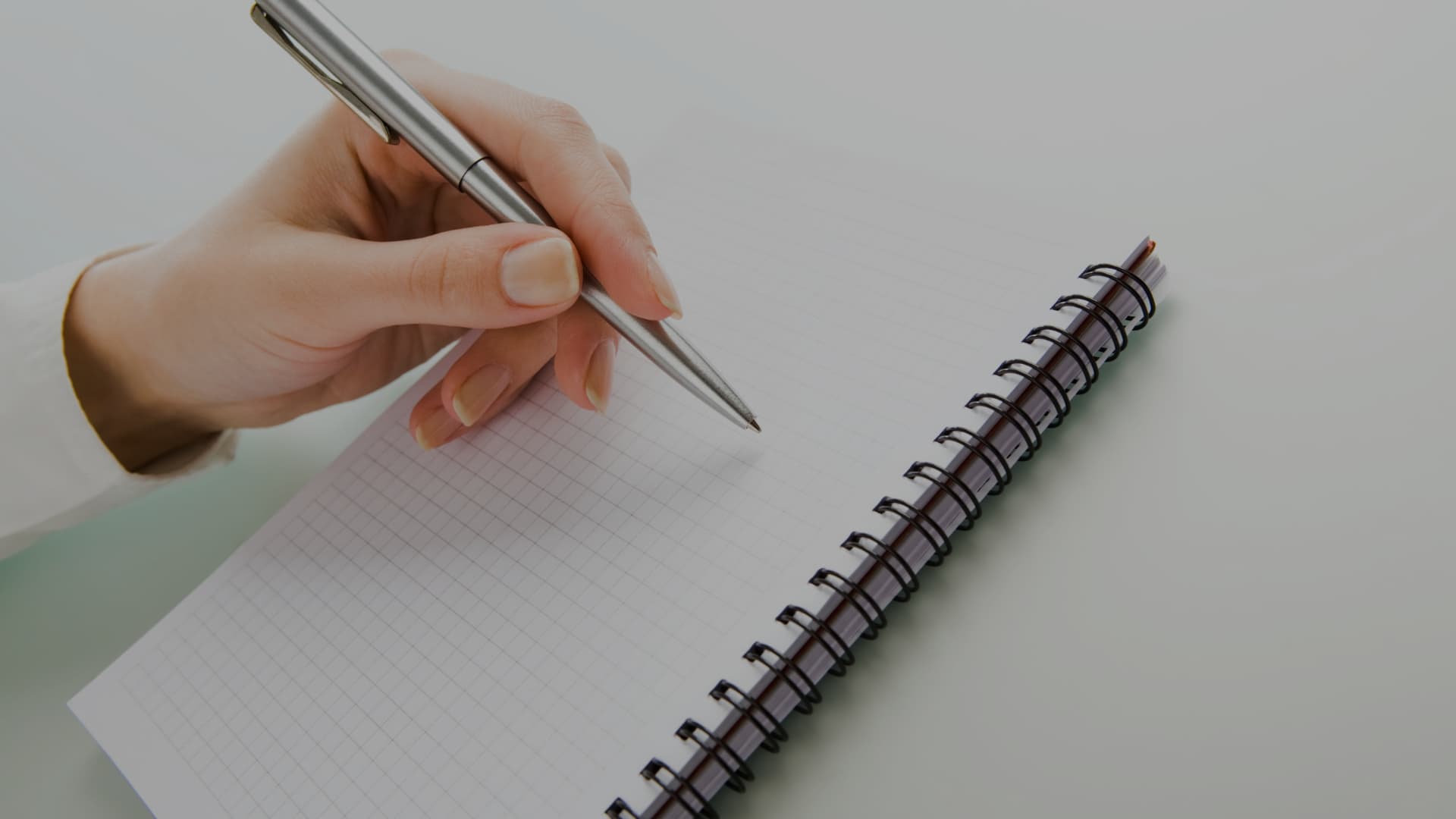 Mano escribiendo en un cuaderno: conectores y marcadores discursivos para el DELE B2