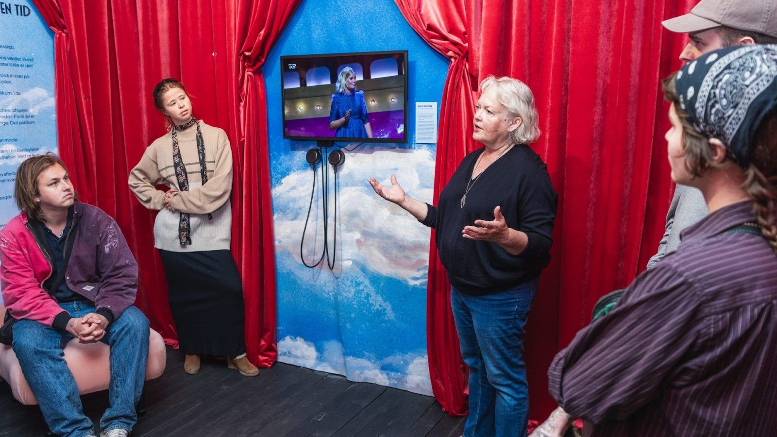 En dame står på STORMS og fortæller et publikum om udstillingen