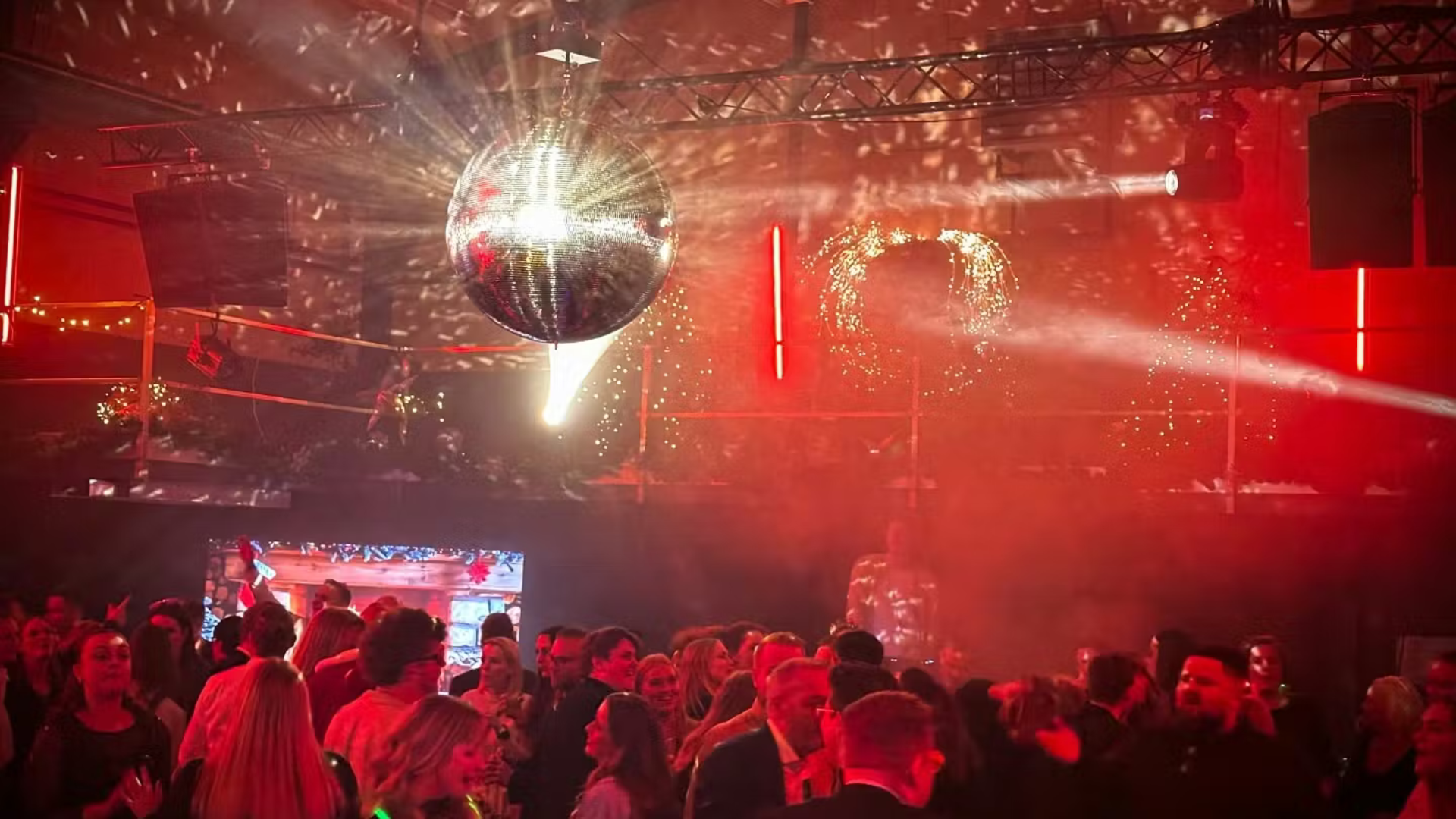 Mennesker der danser under en stor diskokugle på en club