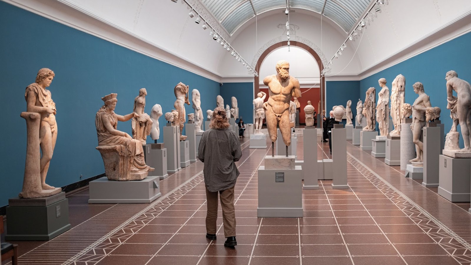 En kvinder der går rundt blandt skulpturerne på Glyptoteket