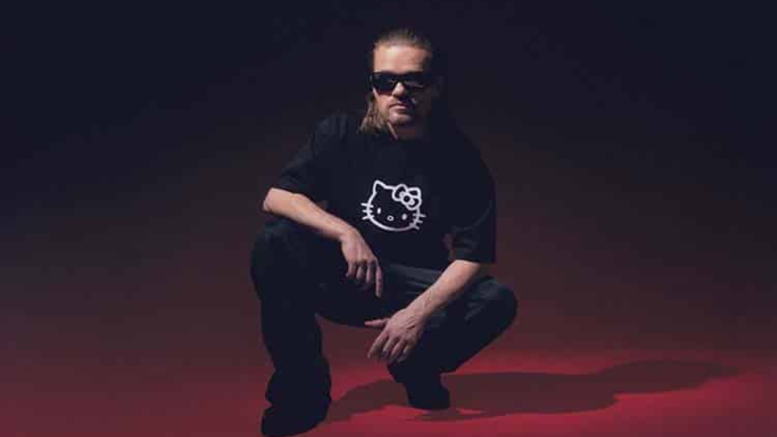 Rune Rask der sidder på hug med solbriller på