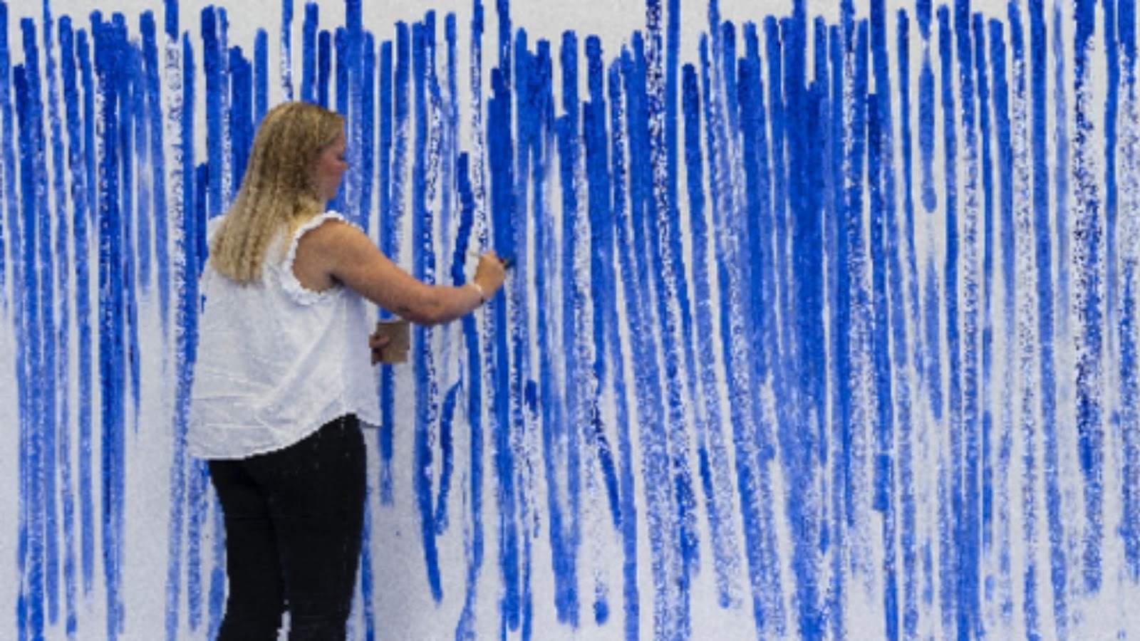En kvinde foran et Jeppe Hein maleri med blå striber og hvid baggrund