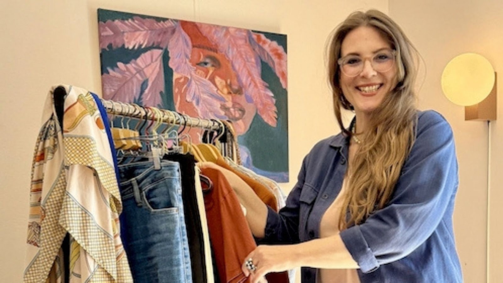 En kvinde foran et tøjstativ fyldt med tøj