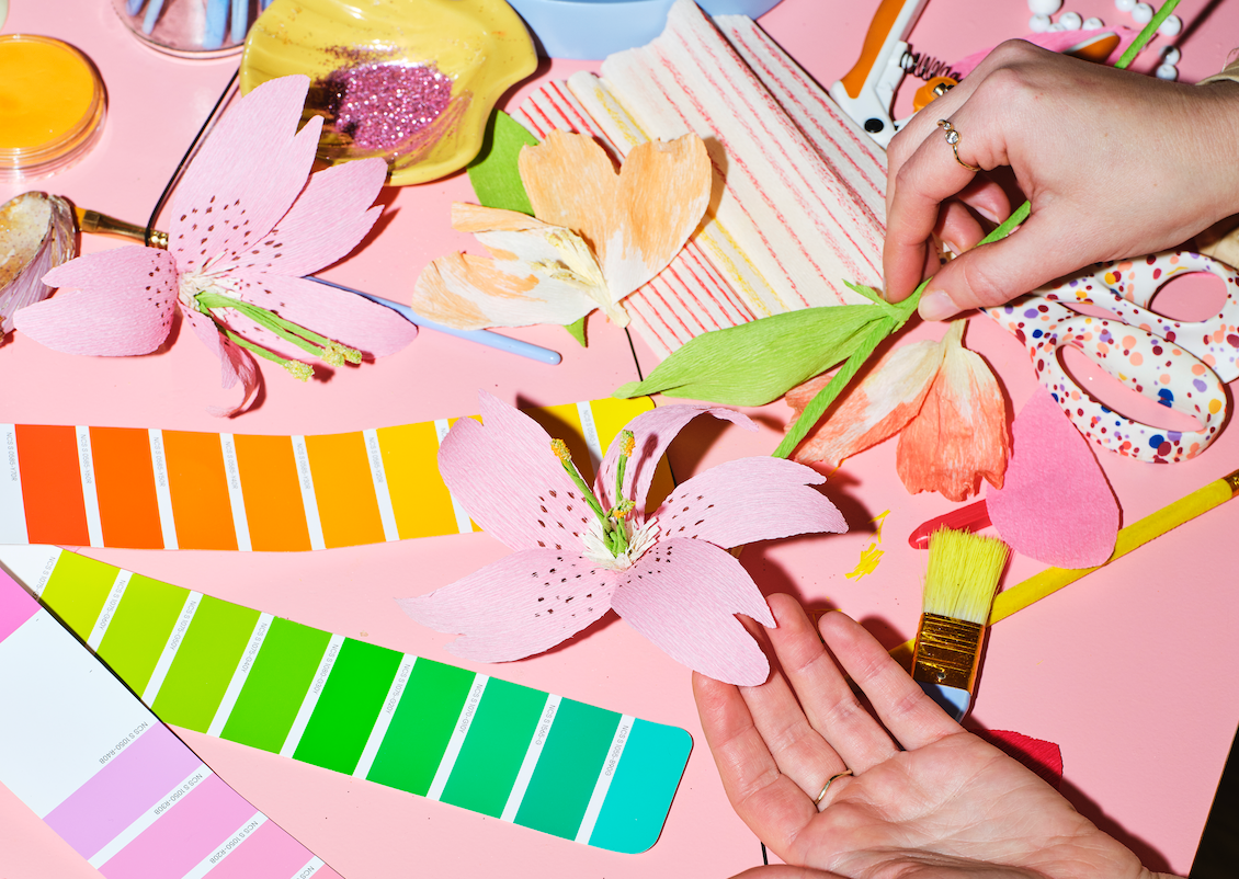 Hænder der er i gang med at samle papirblomster