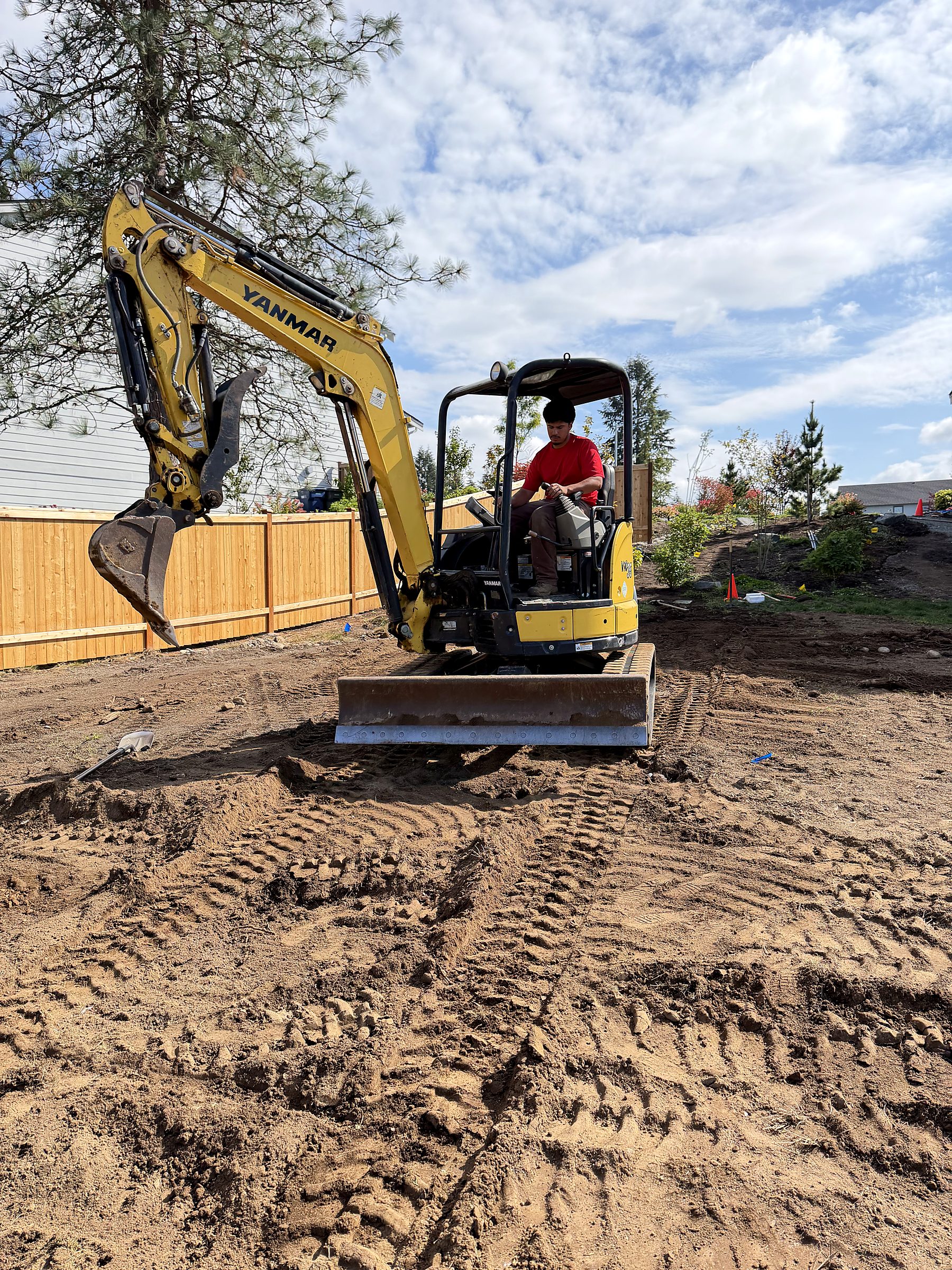 Grizzly Landscape & Construction crew running a mini excavator on a residential site preparation job