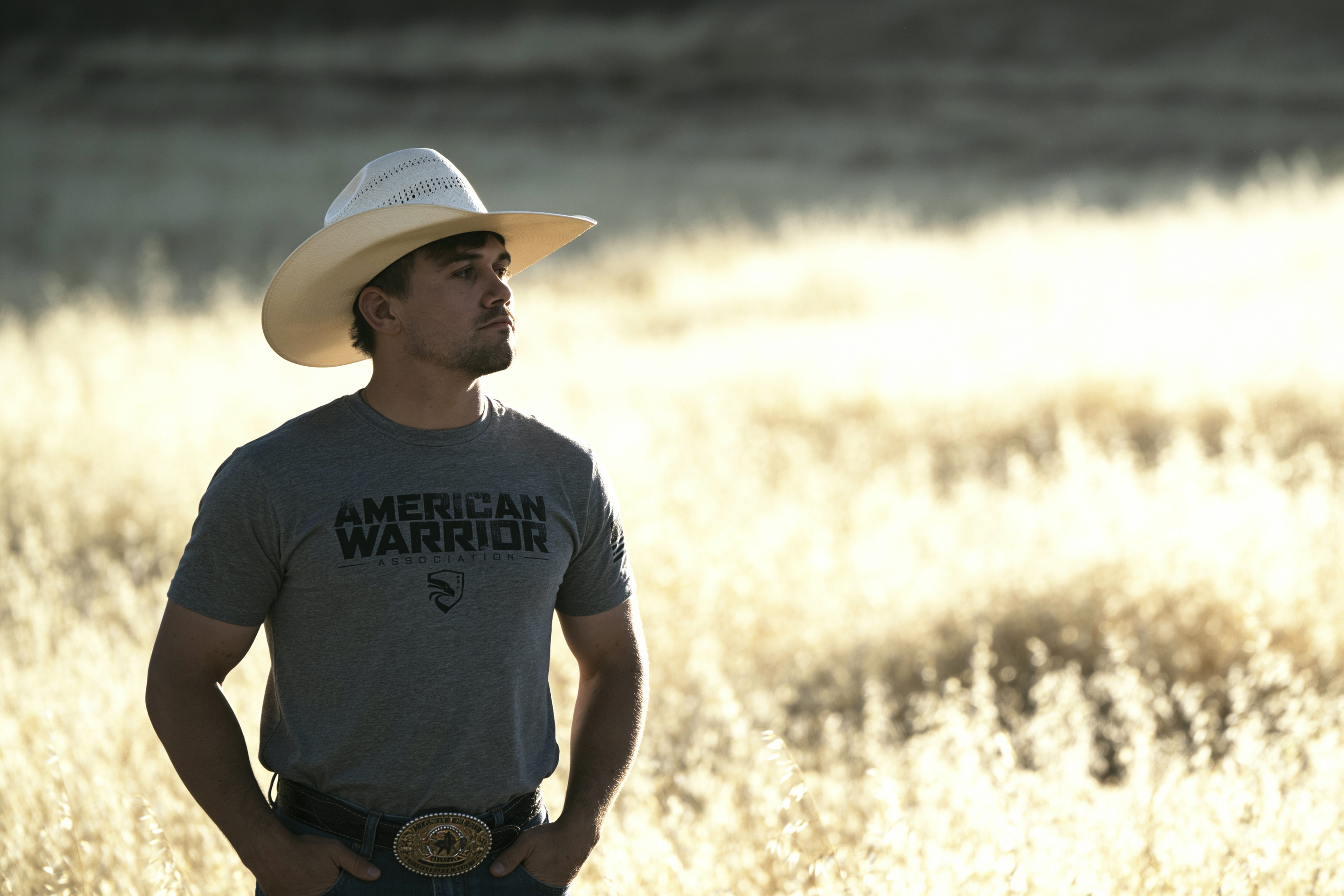 Daylon Swearingen standing in tall dry grass in backlit afternoon sun.