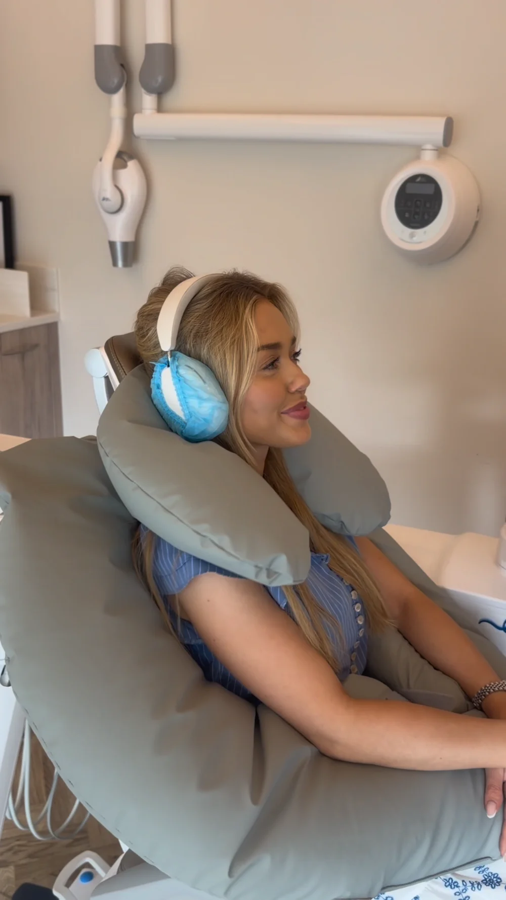 Patient seated with grey neck and arm support cushions and headphones with blue covers.