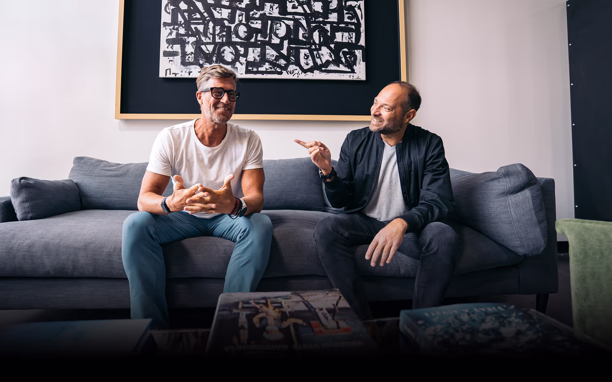 Rich roll and Adam Skolnick sitting together on a grey sofa