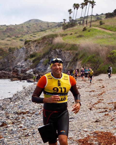 Adam Skolnick runniing in a wesuit on a beach in a Swim Run comp