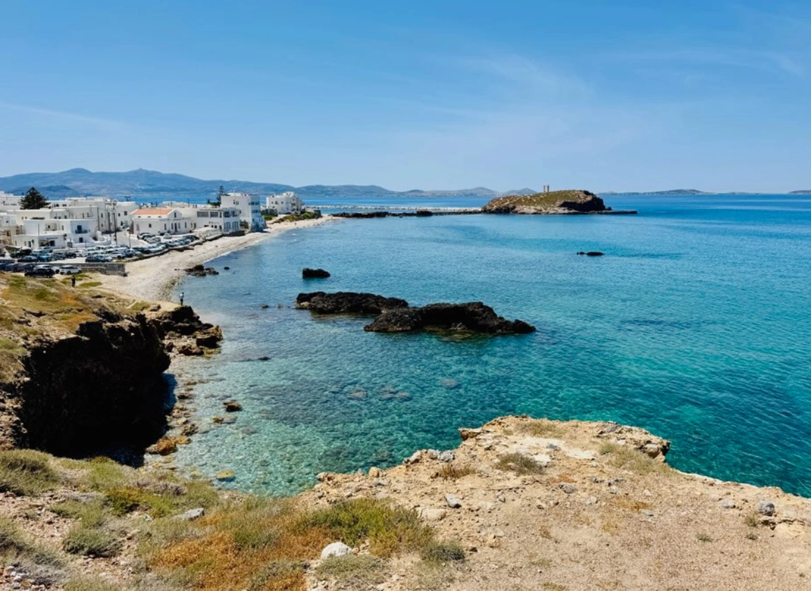 Coastal view of Naxos with whitewashed buildings and clear blue Aegean waters.