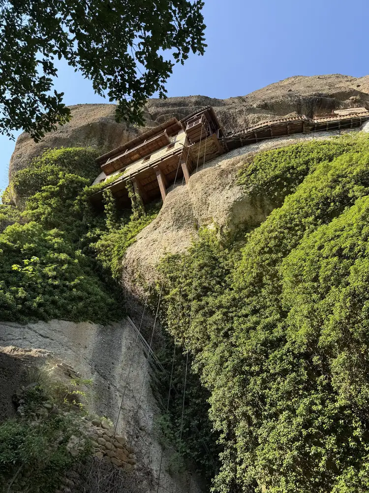 A tiny hermitage tucked into a greenery-covered cliff in Meteora
