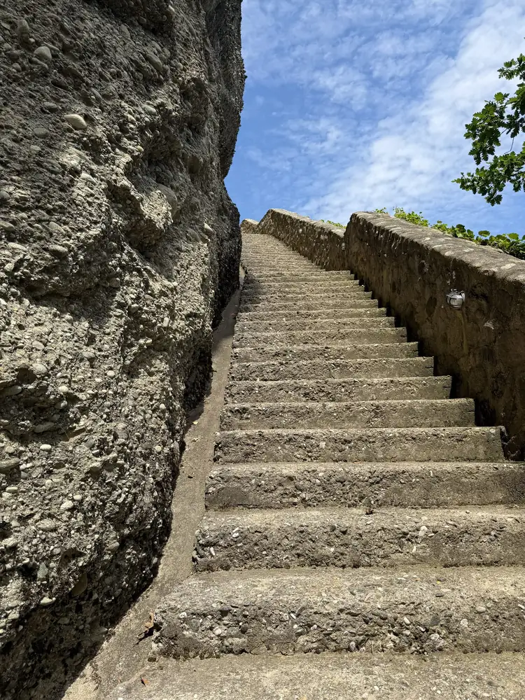 Stone steps climbing alongside a rock pillar toward a monastery