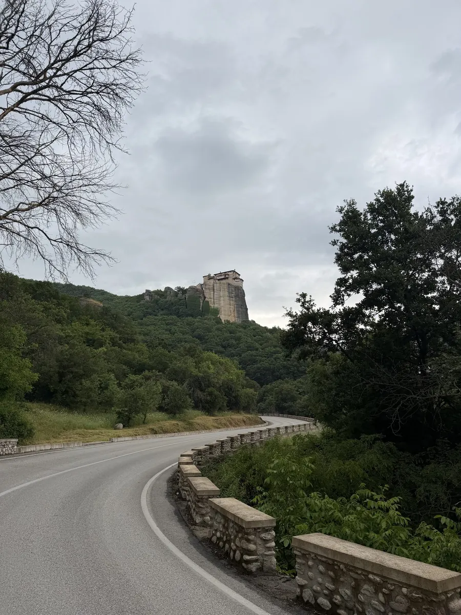 Quiet road below Kastraki curving toward a monastery crowning the rock