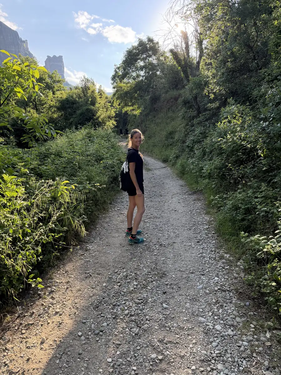 A retreat guest hiking a forest trail beneath the rock towers of Meteora