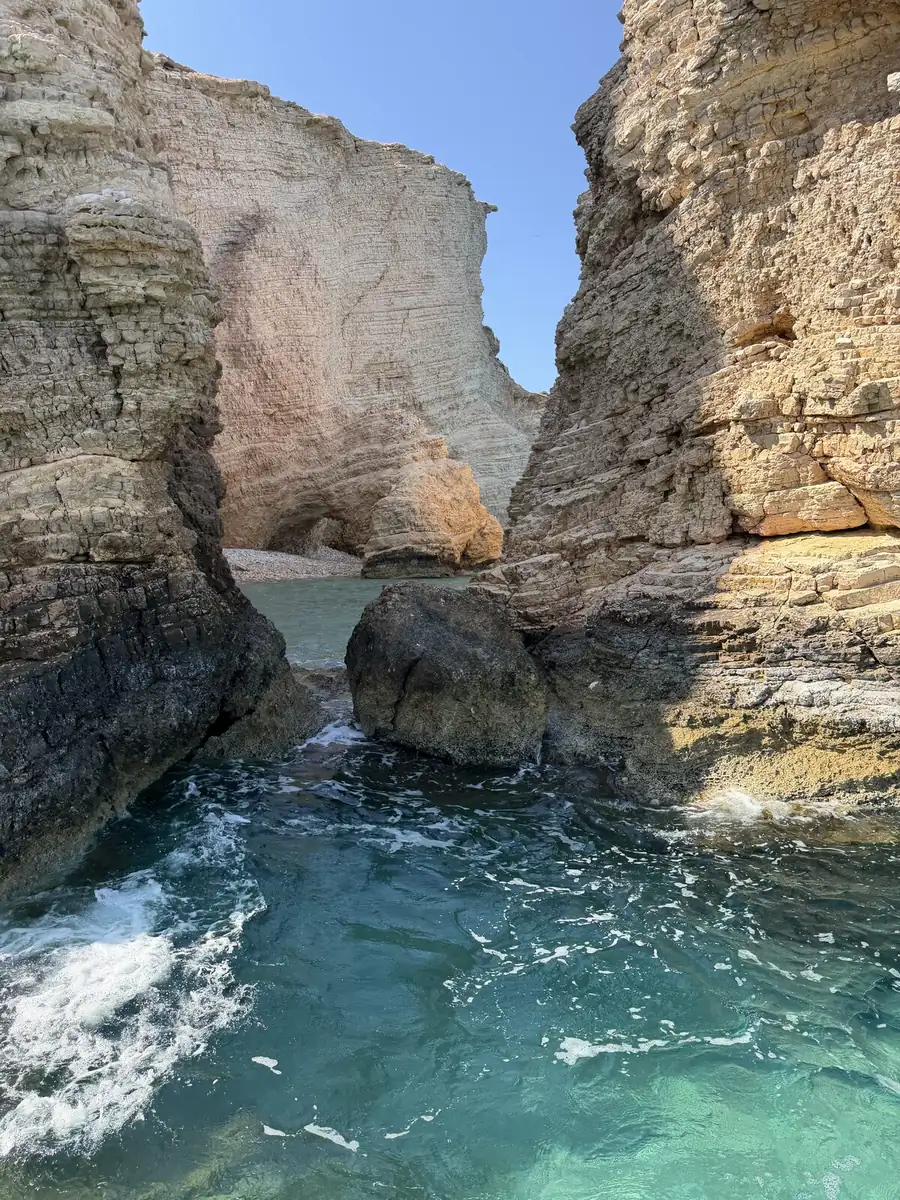 A sea cave carved through the rock above clear turquoise water