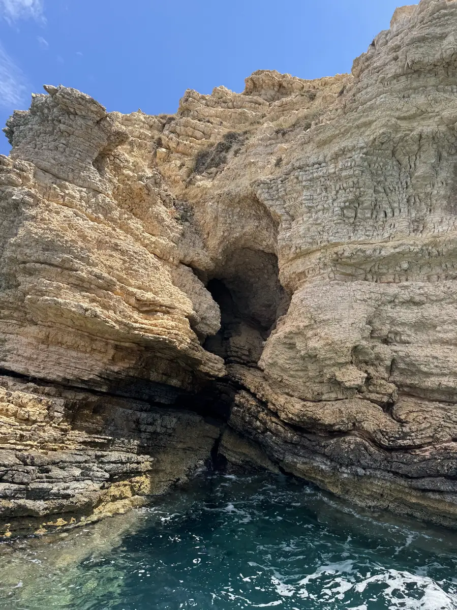 A sea cave cut into the rock above clear turquoise water