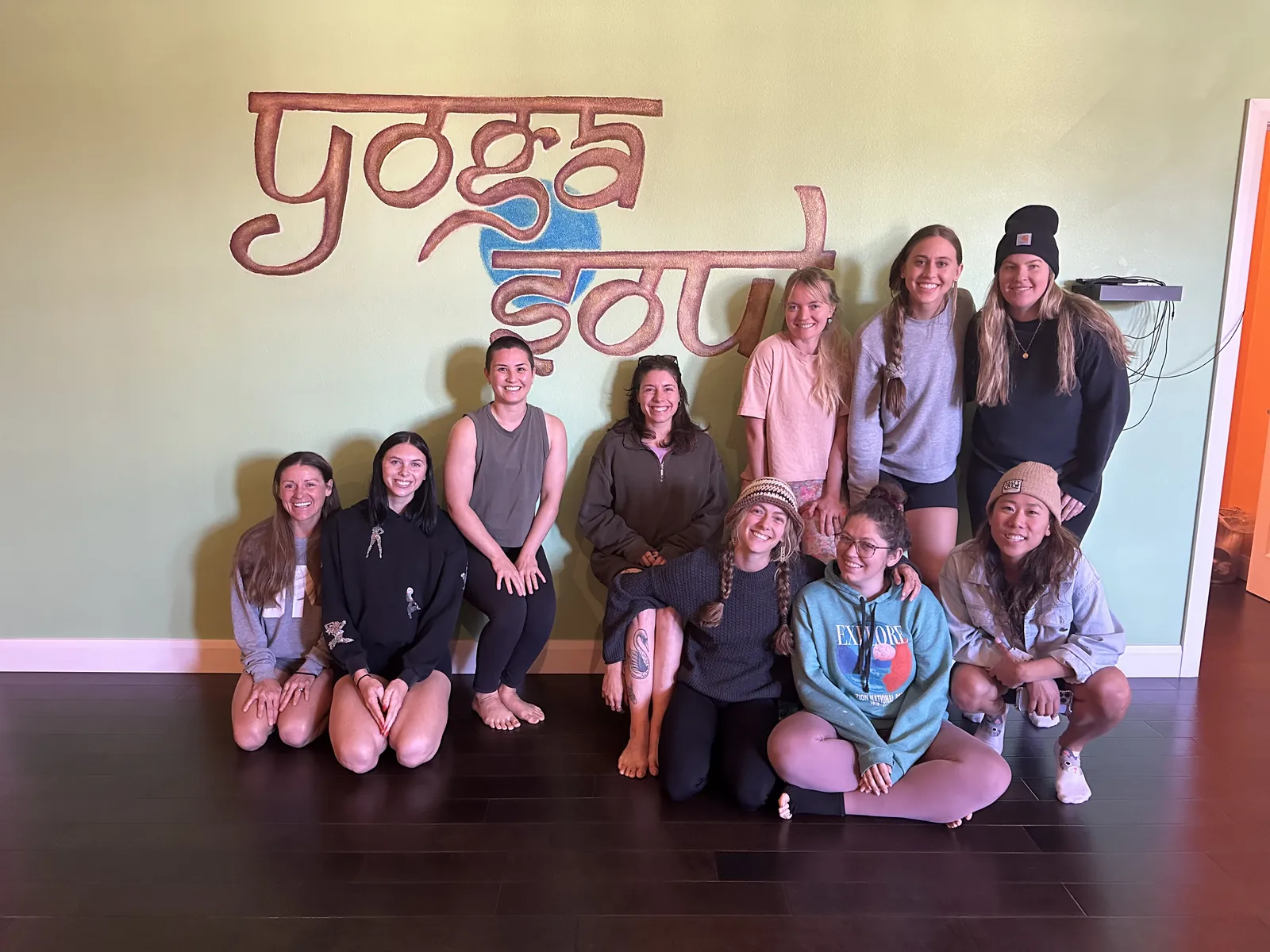 A graduating YogaSoul teacher training cohort in front of the YogaSoul sign