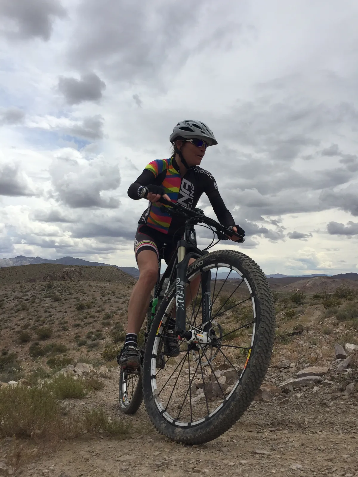 Rachel Cieslewicz mountain biking under a storm sky
