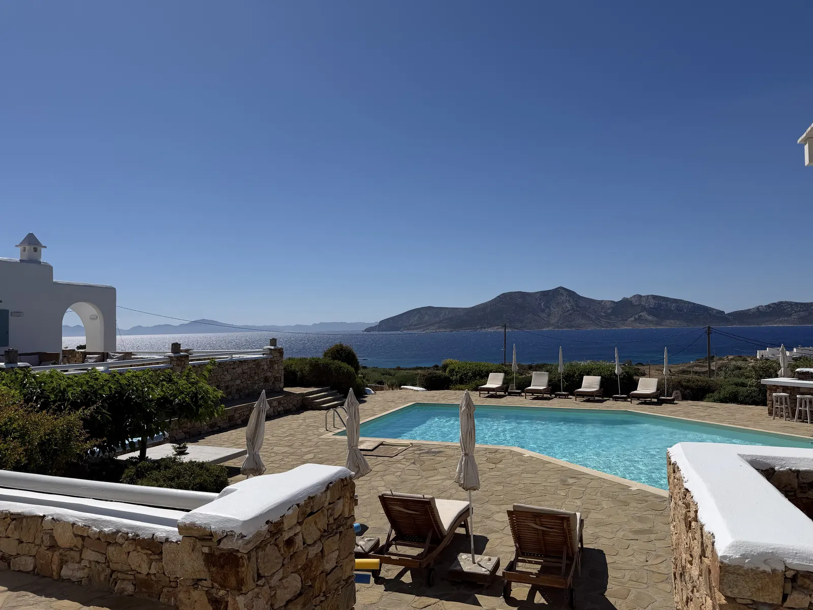 The estate pool and sun loungers, with the sea and neighboring islands beyond