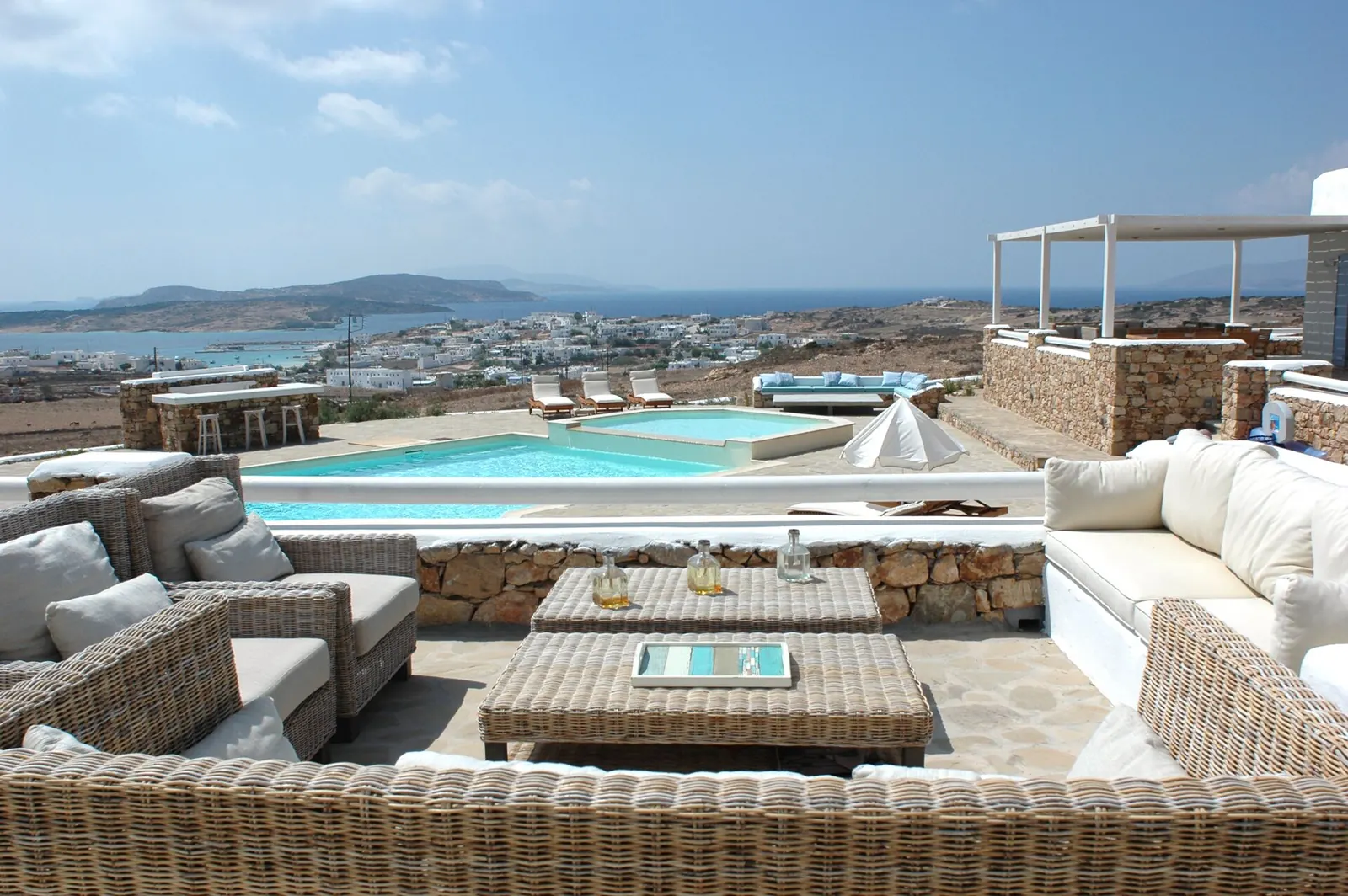 Outdoor lounge seating on a terrace above the estate pool, the sea beyond