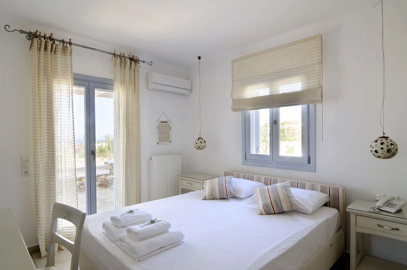 A white bedroom with a double bed beneath a shuttered window